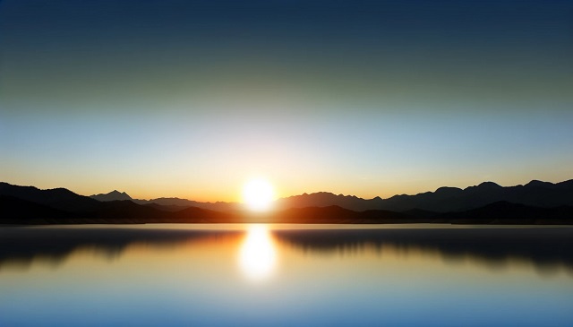 Baner do strony Mój Prąd Mrągowo. Spokojny krajobraz o świcie, ukazujący harmonijną mieszankę wschodzącego słońca nad spokojnym jeziorem z sylwetką odległych gór i czystego nieba.